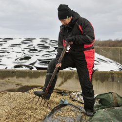 Person if�rt sort strikhue og regnt�j ved kysten, arbejde i bl�sende vejr.